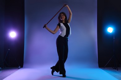 Photo of Teenage girl in tap shoes with cane dancing on color background
