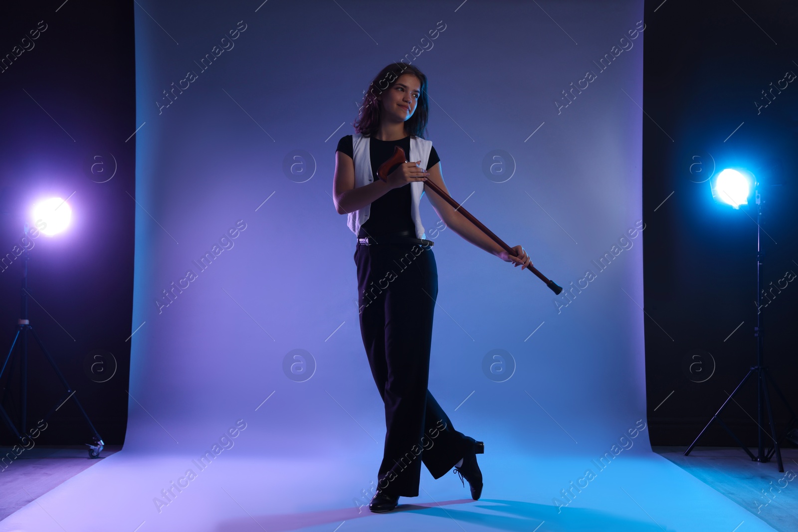 Teenage girl in tap shoes with cane dancing on color background Photo of Teenage girl in tap shoes with cane dancing on color background