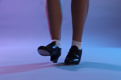 Photo of Teenage girl in tap shoes dancing on color background, closeup