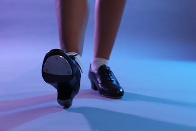 Photo of Teenage girl in tap shoes dancing on color background, closeup