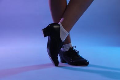 Photo of Teenage girl in tap shoes dancing on color background, closeup