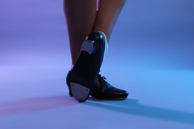 Photo of Teenage girl in tap shoes dancing on color background, closeup