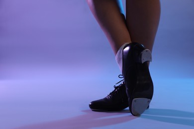 Photo of Teenage girl in tap shoes dancing on color background, closeup. Space for text
