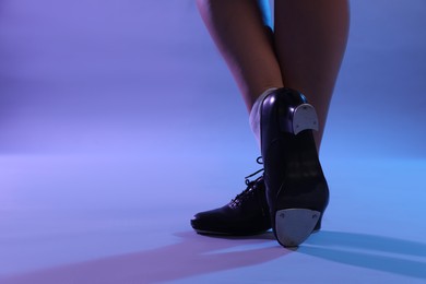 Photo of Teenage girl in tap shoes dancing on color background, closeup. Space for text