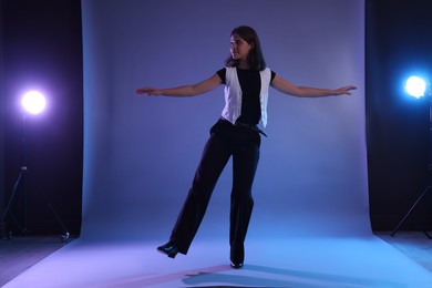Photo of Teenage girl in tap shoes dancing on color background