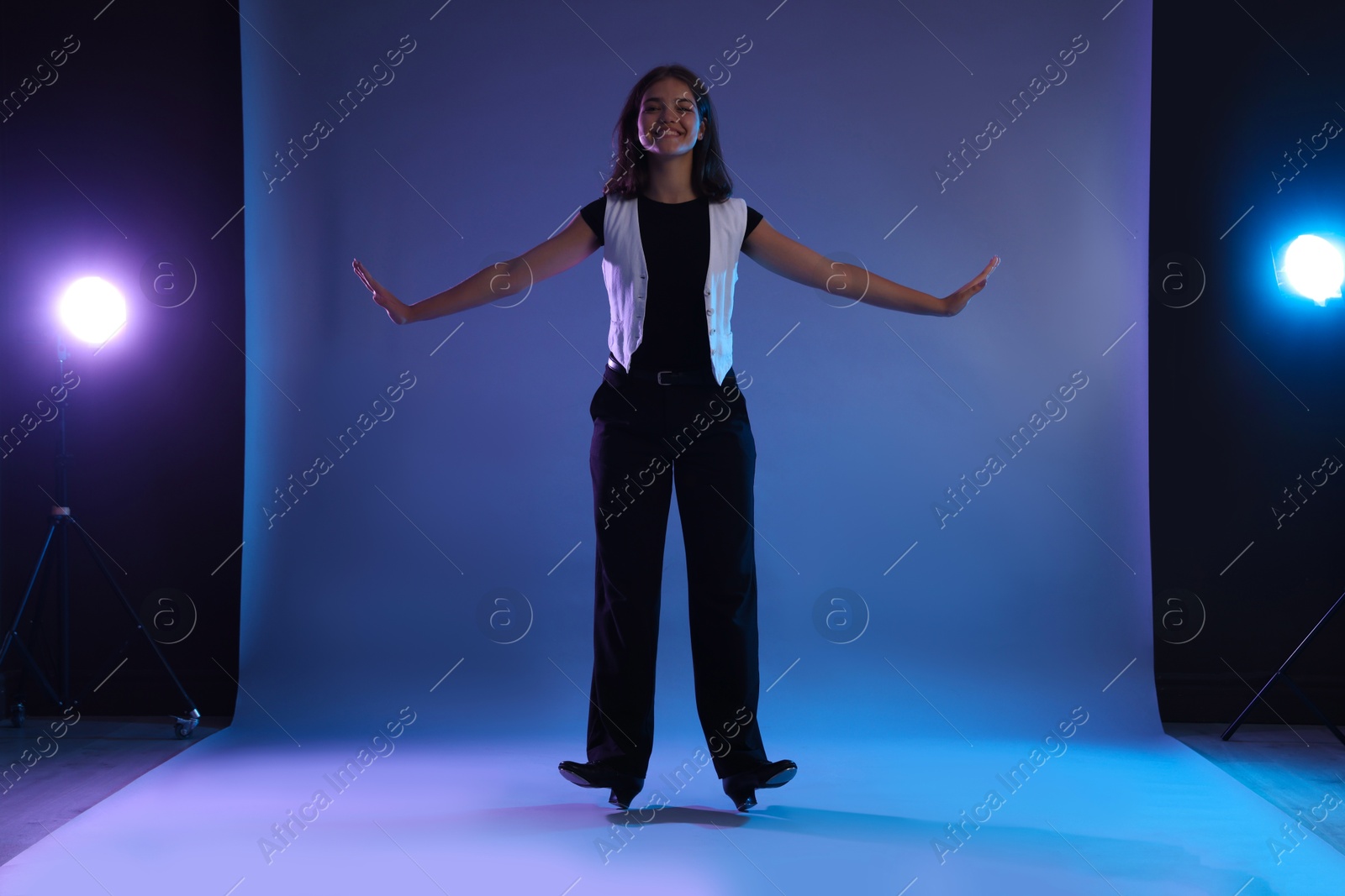 Teenage girl in tap shoes dancing on color background Photo of Teenage girl in tap shoes dancing on color background
