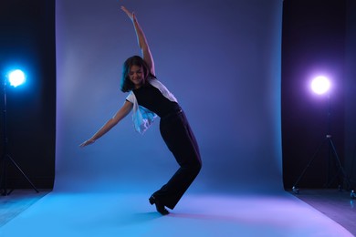 Photo of Teenage girl in tap shoes dancing on color background