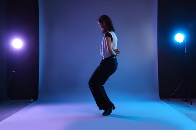 Photo of Teenage girl in tap shoes dancing on color background