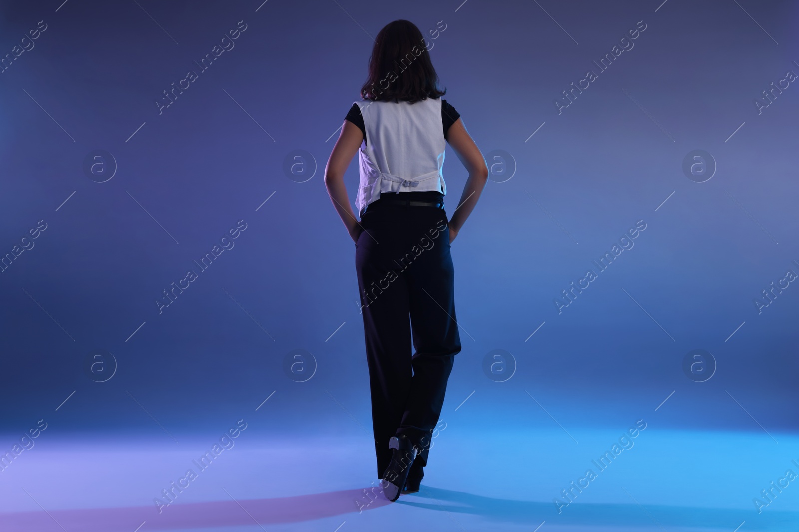 Teenage girl in tap shoes dancing on color background, back view Photo of Teenage girl in tap shoes dancing on color background, back view