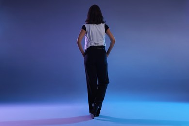 Photo of Teenage girl in tap shoes dancing on color background, back view