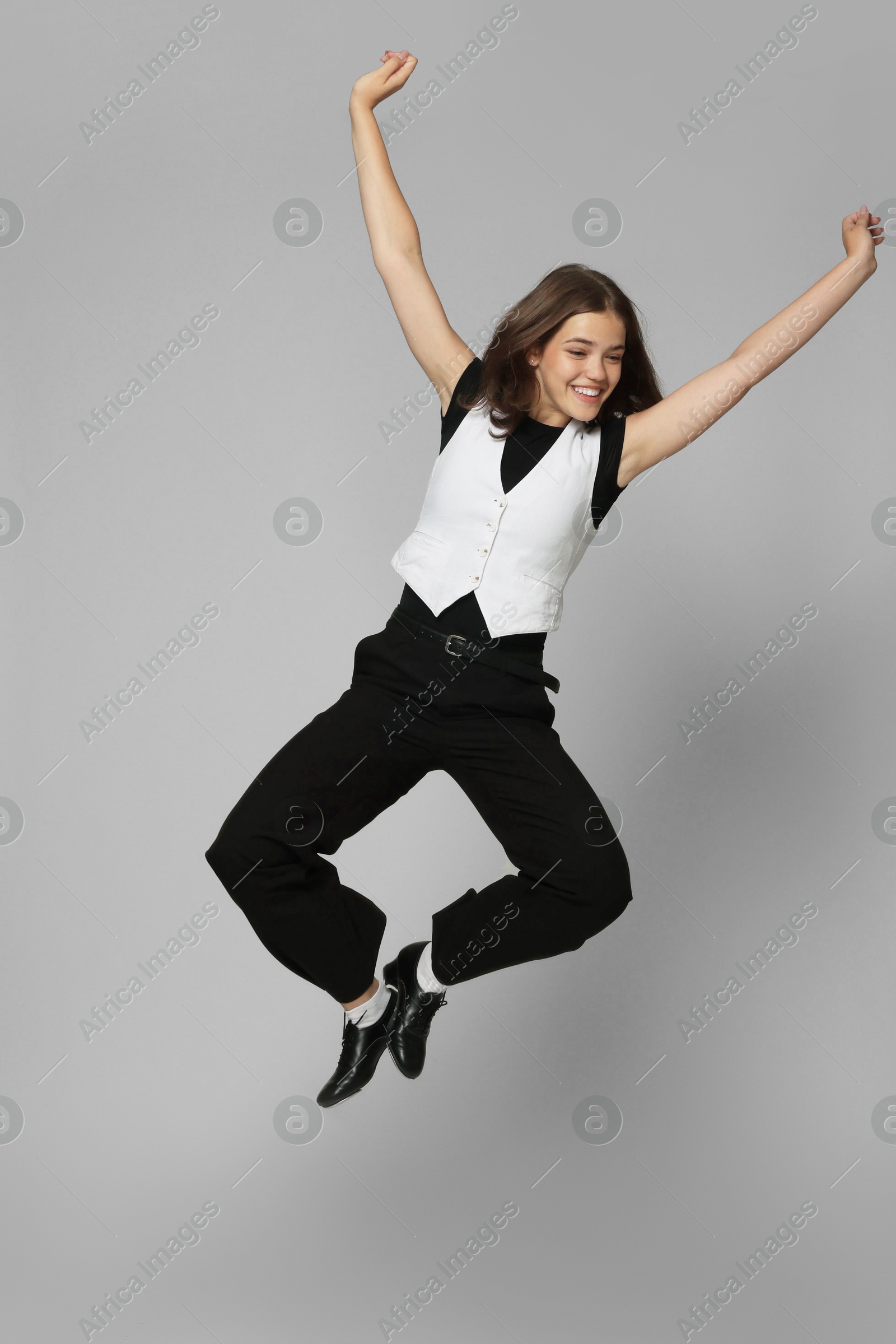 Teenage girl in tap shoes dancing on light grey background Photo of Teenage girl in tap shoes dancing on light grey background