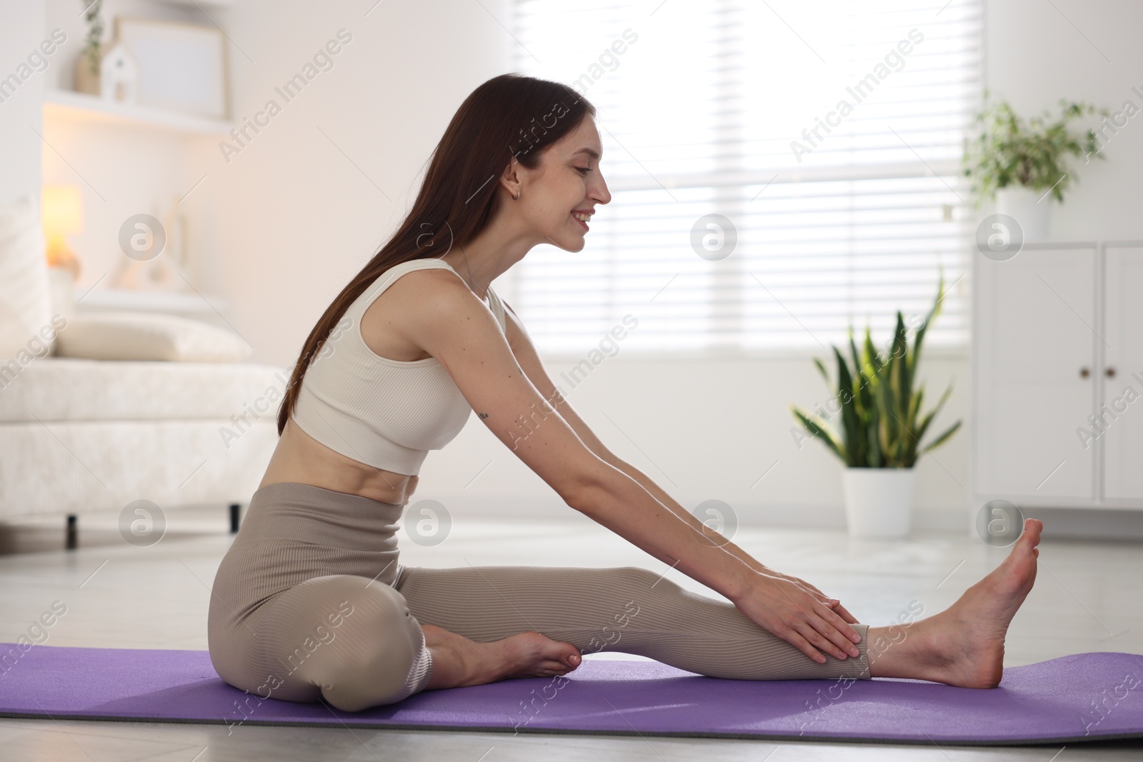 Smiling woman in sportswear stretching on mat at home Photo of Smiling woman in sportswear stretching on mat at home