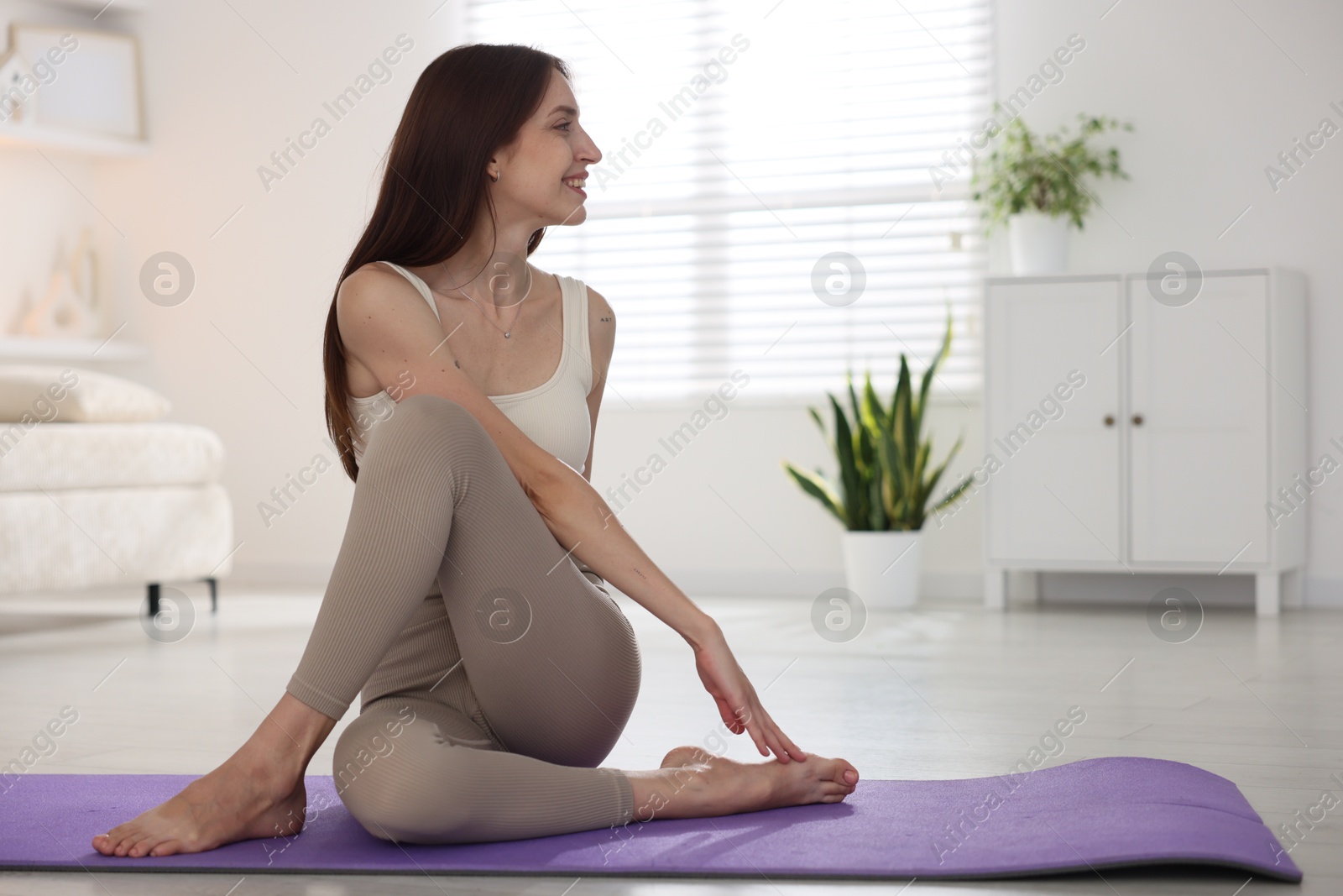 Smiling woman in sportswear stretching on mat at home. Space for text Photo of Smiling woman in sportswear stretching on mat at home. Space for text