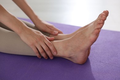 Photo of Woman stretching on mat at home, closeup