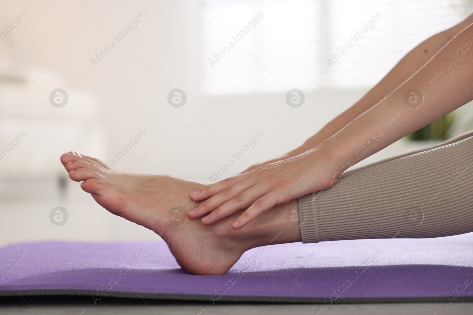 Woman stretching on mat at home, closeup Photo of Woman stretching on mat at home, closeup
