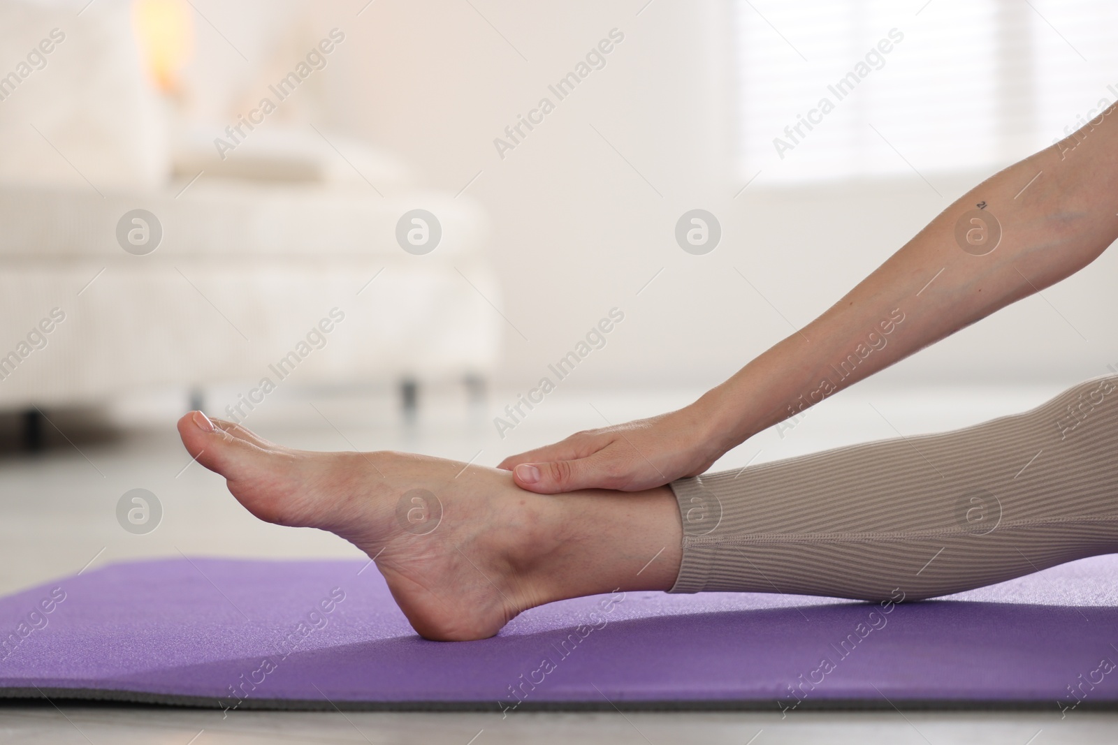 Woman stretching on mat at home, closeup Photo of Woman stretching on mat at home, closeup