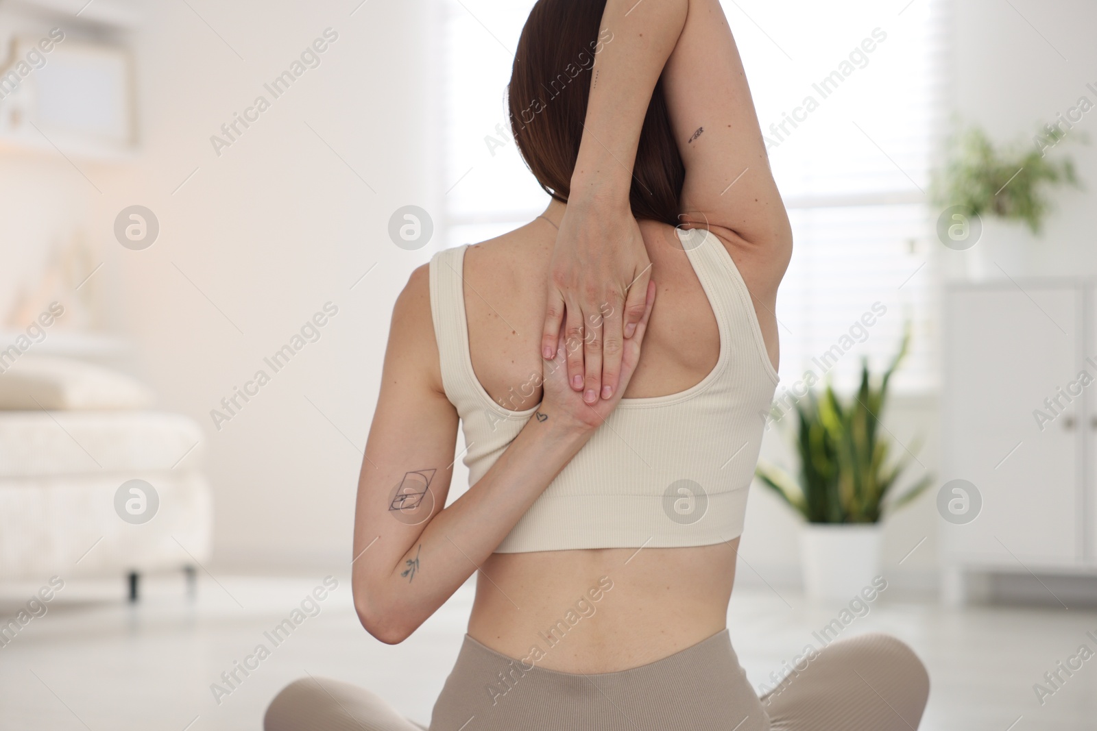 Woman in sportswear stretching at home, back view Photo of Woman in sportswear stretching at home, back view