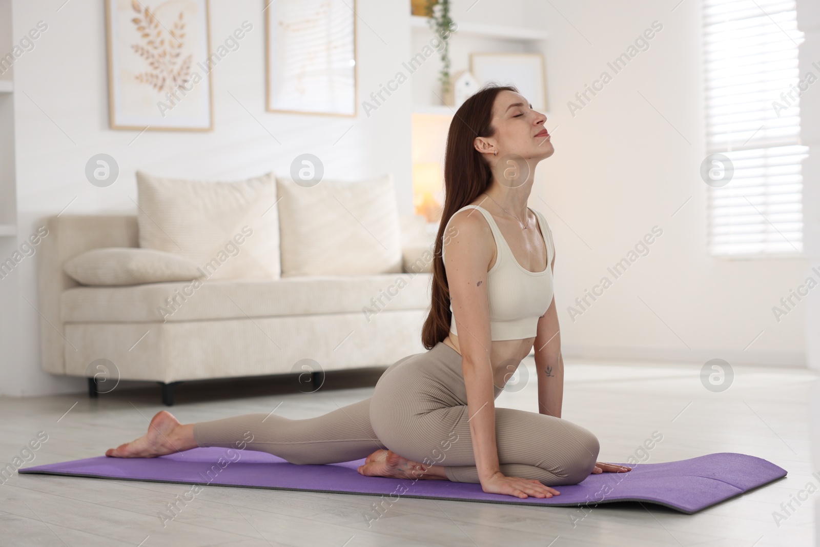 Young woman in sportswear stretching on mat at home Photo of Young woman in sportswear stretching on mat at home