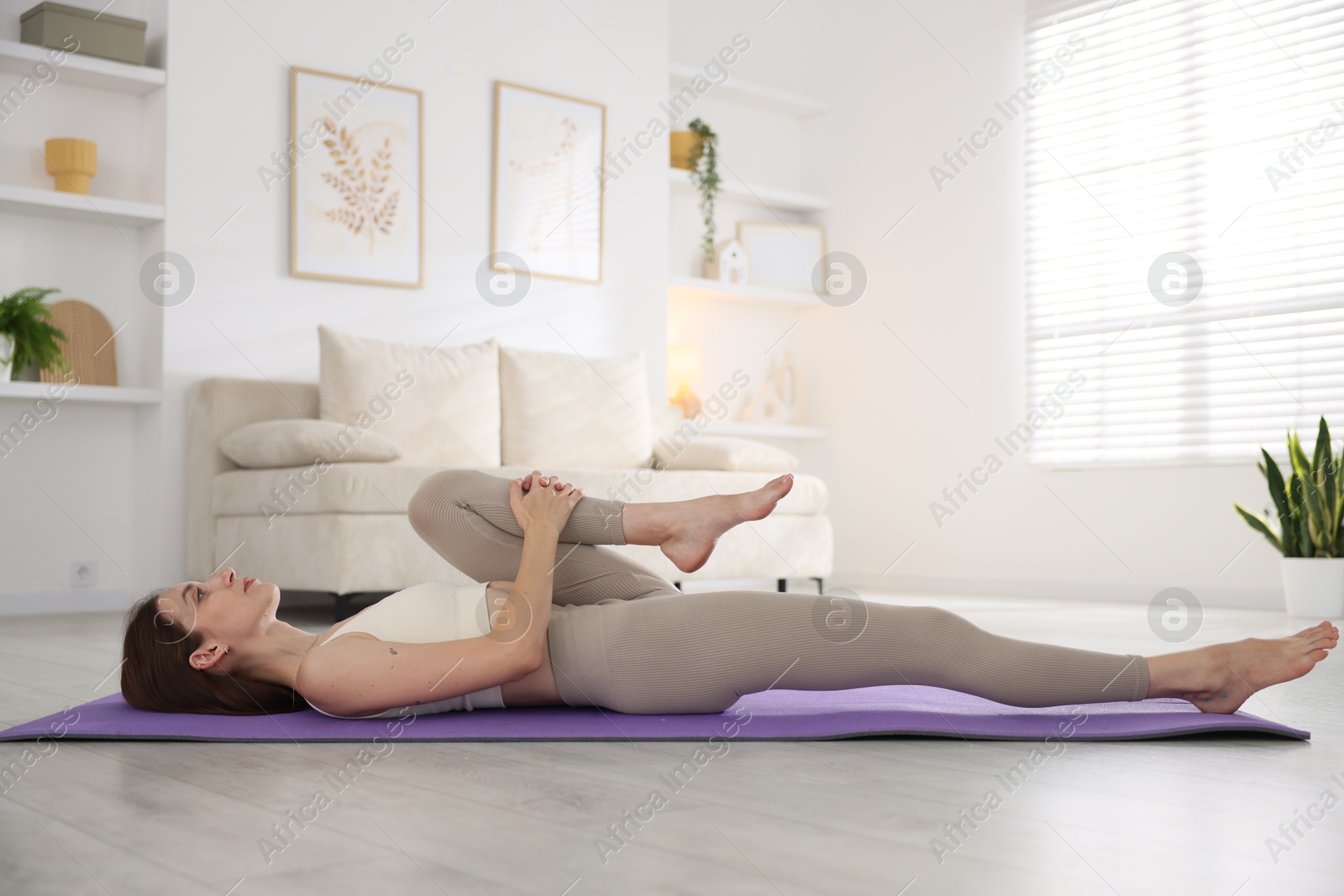 Young woman in sportswear stretching on mat at home Photo of Young woman in sportswear stretching on mat at home