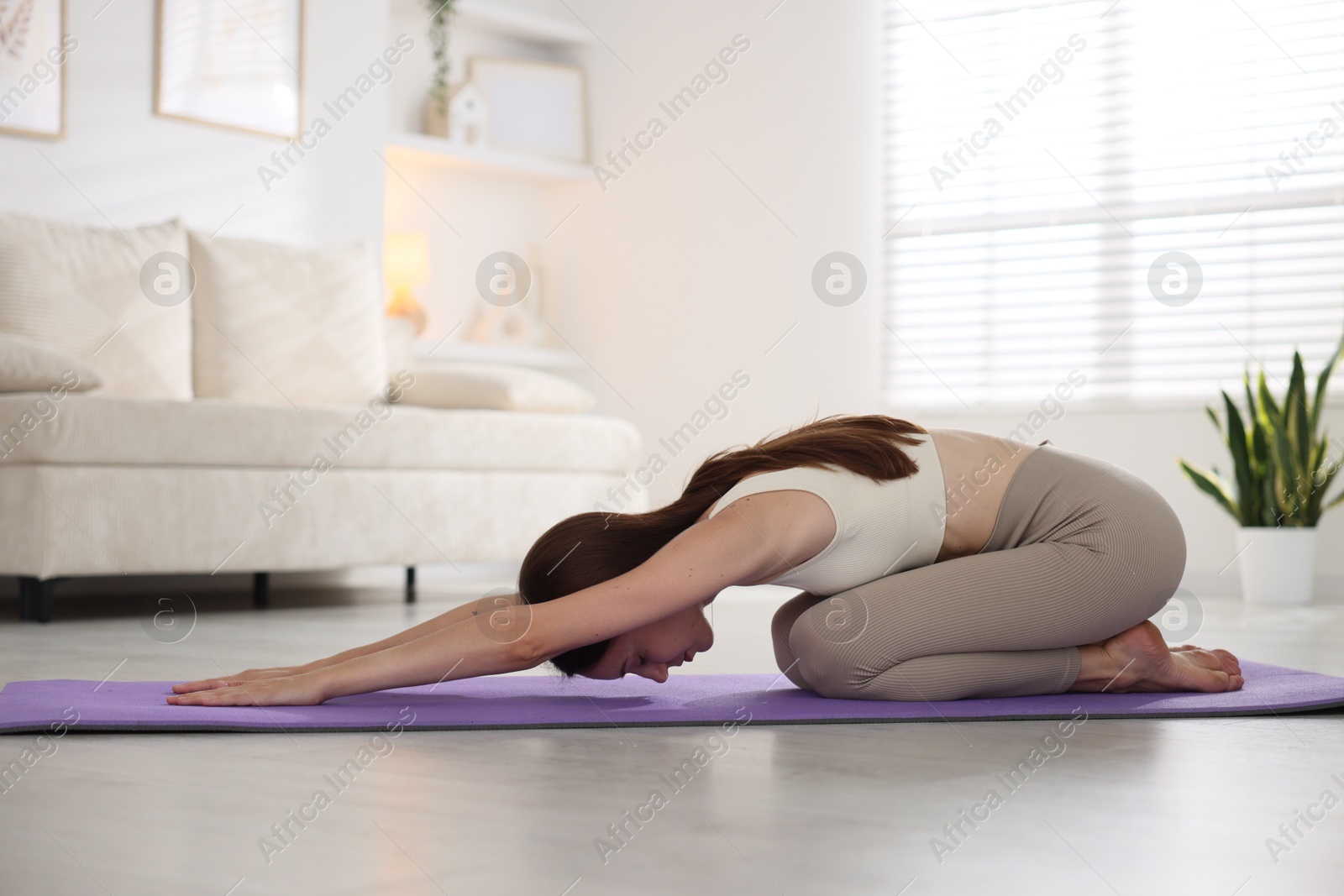 Young woman in sportswear stretching on mat at home Photo of Young woman in sportswear stretching on mat at home
