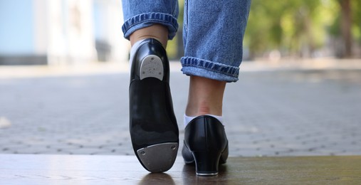 Photo of Teenage girl in tap shoes dancing outdoors, closeup