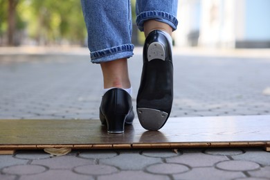 Photo of Teenage girl in tap shoes dancing outdoors, closeup