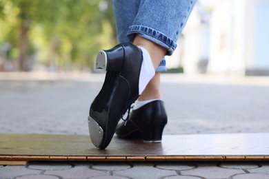 Photo of Teenage girl in tap shoes dancing outdoors, closeup