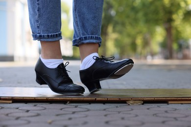 Photo of Teenage girl in tap shoes dancing outdoors, closeup