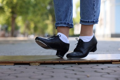 Photo of Teenage girl in tap shoes dancing outdoors, closeup