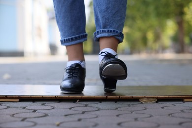 Photo of Teenage girl in tap shoes dancing outdoors, closeup