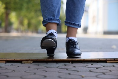 Photo of Teenage girl in tap shoes dancing outdoors, closeup
