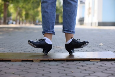 Photo of Teenage girl in tap shoes dancing outdoors, closeup