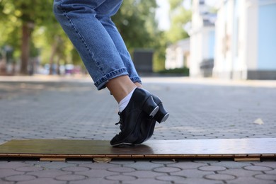 Photo of Teenage girl in tap shoes dancing outdoors, closeup