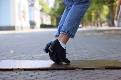 Photo of Teenage girl in tap shoes dancing outdoors, closeup