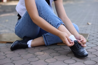 Photo of Teenage girl putting on tap shoes outdoors, closeup