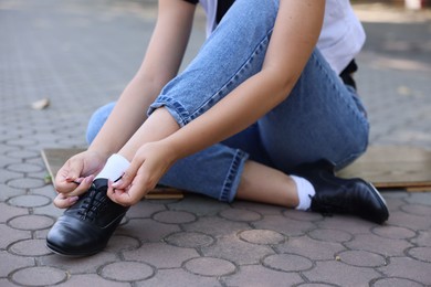 Photo of Teenage girl putting on tap shoes outdoors, closeup