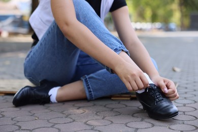 Photo of Teenage girl putting on tap shoes outdoors, closeup