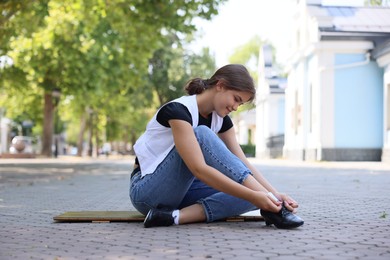 Photo of Teenage girl putting on tap shoes outdoors