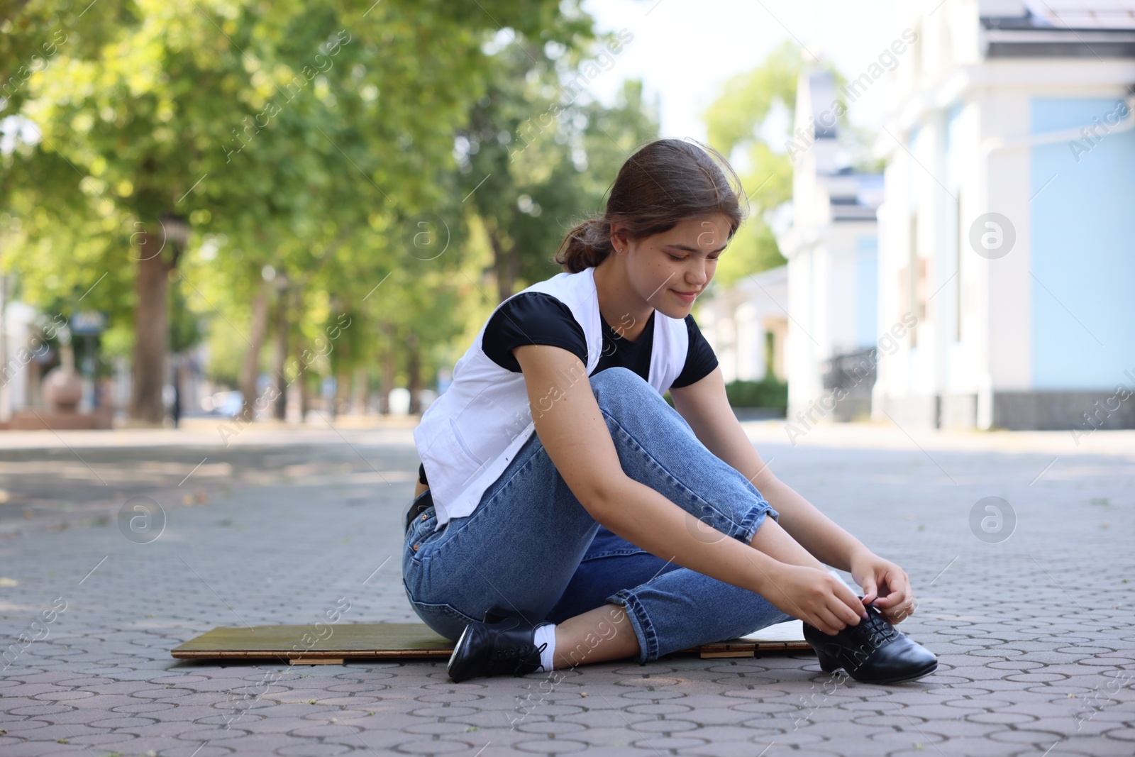 Teenage girl putting on tap shoes outdoors Photo of Teenage girl putting on tap shoes outdoors