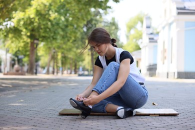 Photo of Teenage girl putting on tap shoes outdoors