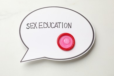 Photo of Speech bubble with phrase Sex Education and condom on white background, top view