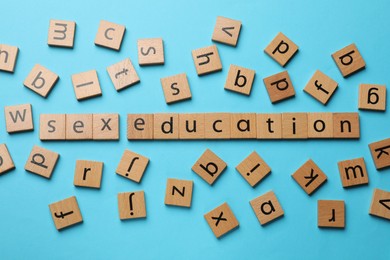 Photo of Phrase Sex Education made with wooden letters on blue background, flat lay