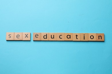 Photo of Phrase Sex Education made with wooden letters on blue background, top view