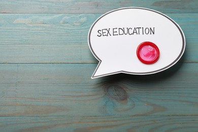 Photo of Speech bubble with phrase Sex Education and condom on blue wooden background, top view