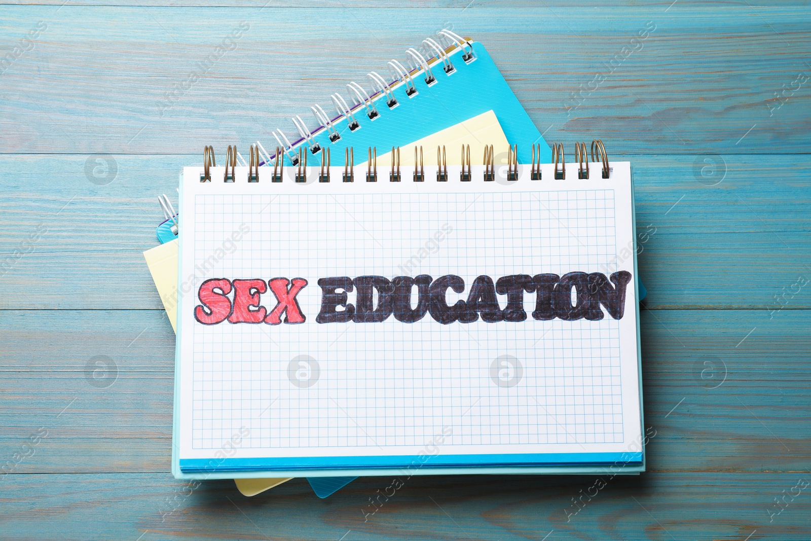 Photo of Notebooks with phrase Sex Education on blue wooden background, top view