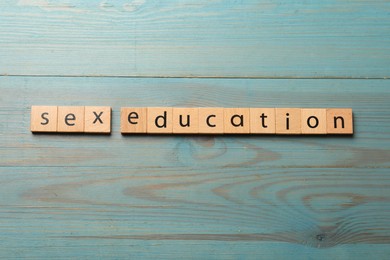 Photo of Phrase Sex Education made with wooden letters on blue table, top view