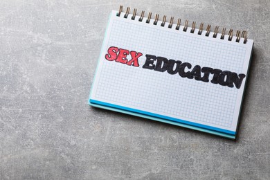 Photo of Phrase Sex Education written in notebook on grey table, top view