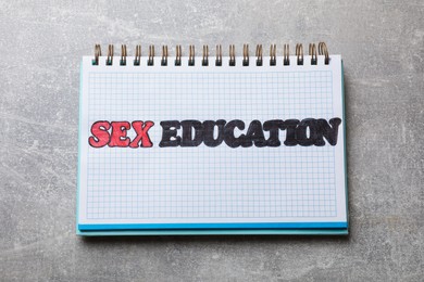 Photo of Phrase Sex Education written in notebook on grey table, top view
