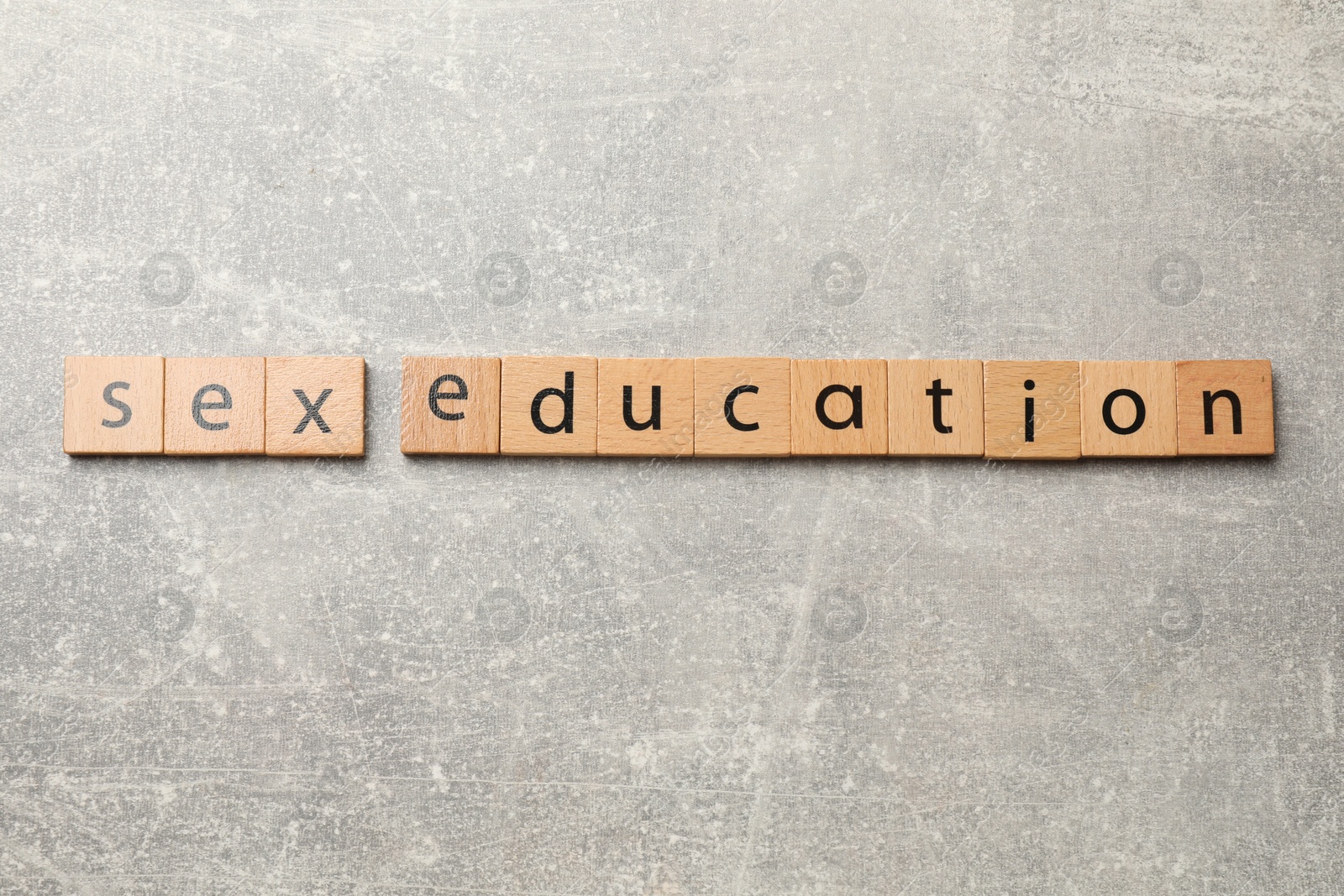 Photo of Phrase Sex Education made of wooden letters on grey table, top view