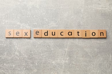 Photo of Phrase Sex Education made of wooden letters on grey table, top view